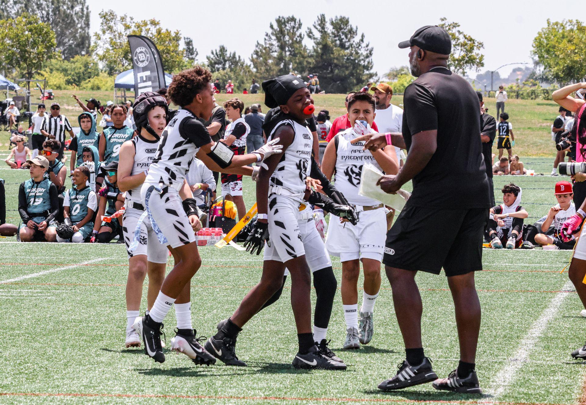 An Apex Predators boys flag football team receiving instruction from Apex founder and coach Omar Smith.