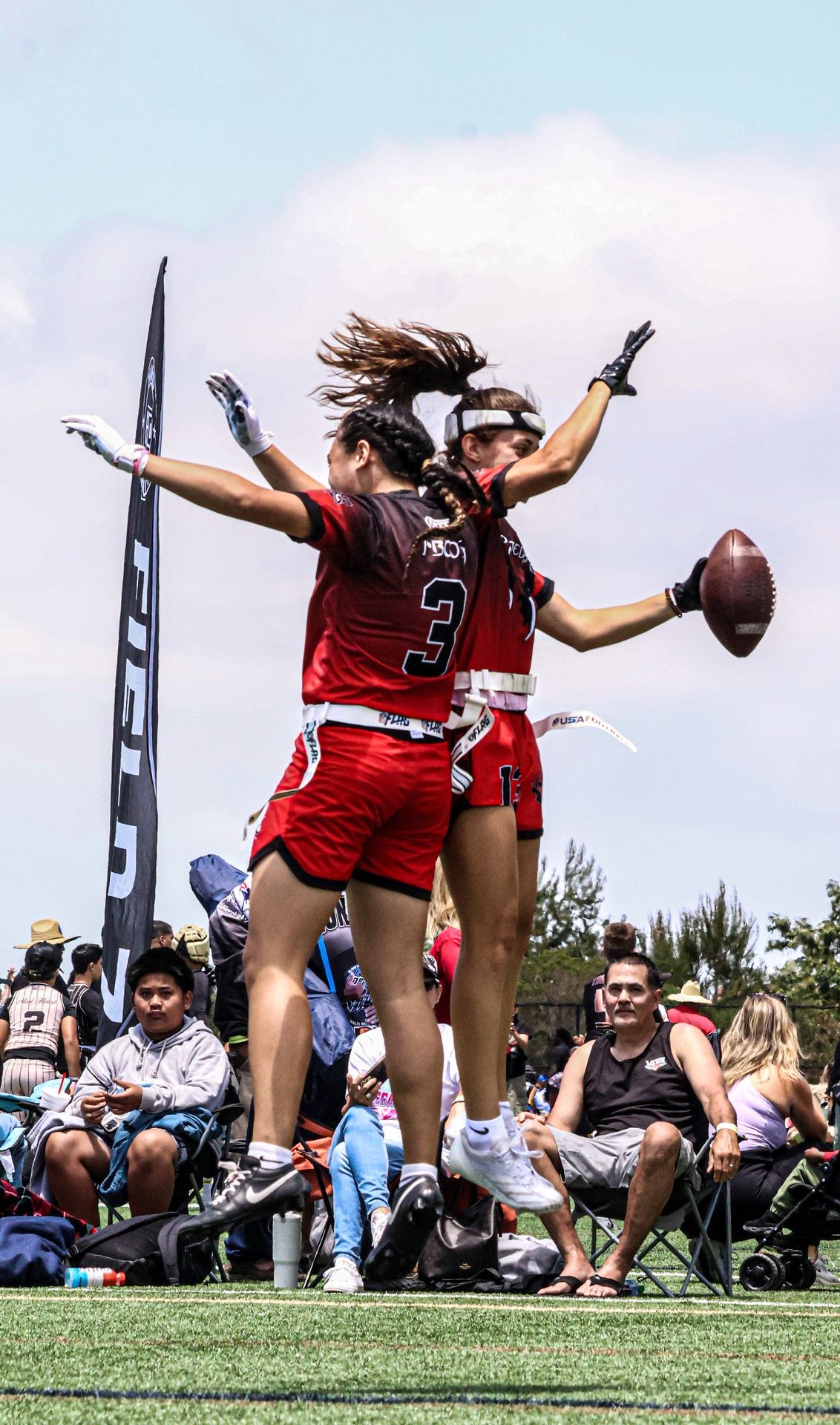 Two Apex Predators flag football players celebrating a touchdown with a jump and a high-five.